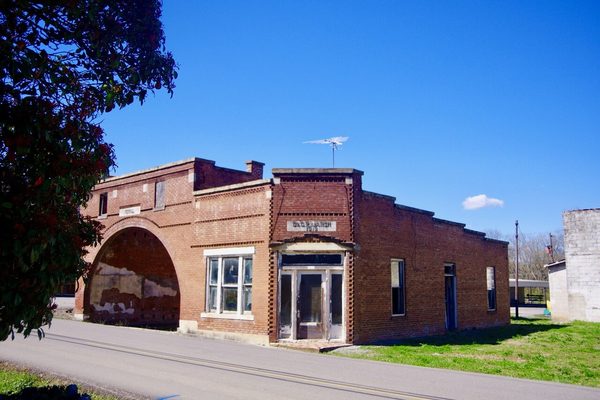 One-story brick commercial building with a large arched opening and a parapet