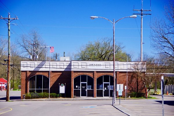 Brick building with three tall arched openings and a flag on a pole