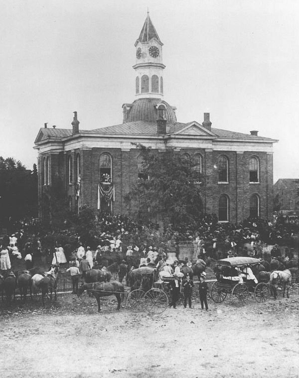 Black-and-white photo of a large crowd gathered in front of the old domed Lincoln County Courthouse