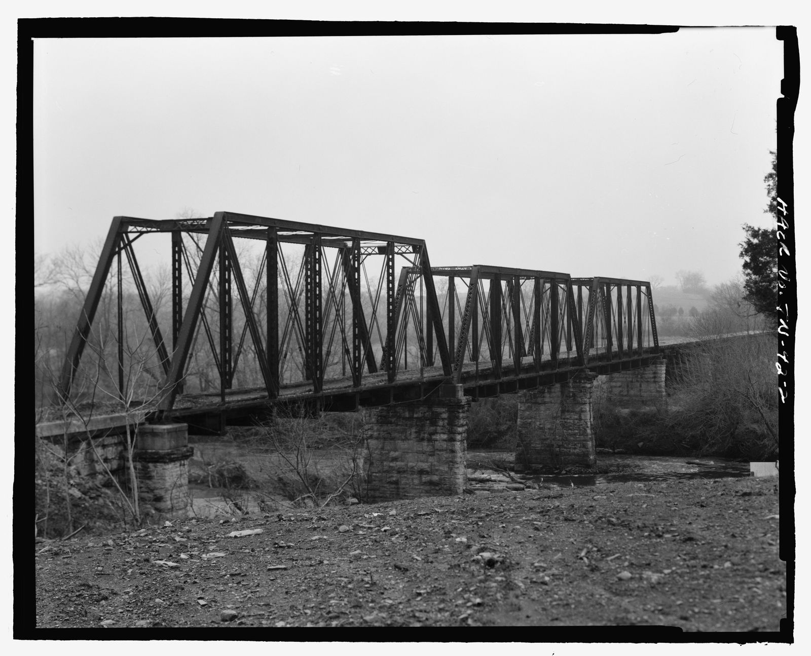 Black-and-white photo of a three-span steel truss railroad bridge crossing the Elk River