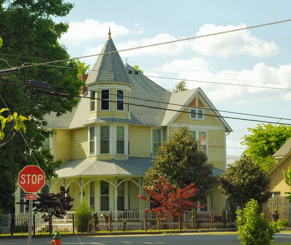 Yellow Queen Anne house with a corner turret and porch