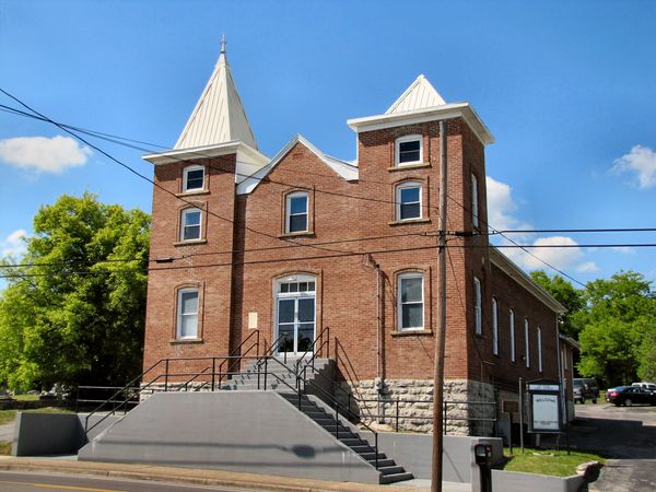 Red brick church with two square towers topped by white spires
