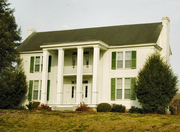 White two-story house with tall columns and green shutters