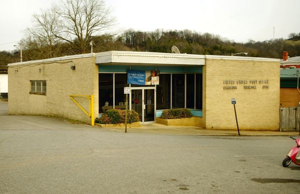 Low tan brick post office building with a flagpole