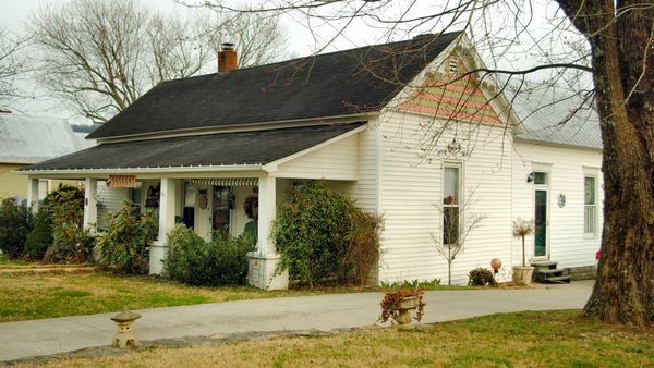 White frame cottage with a porch under bare trees