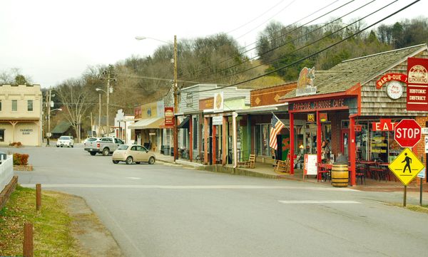 A small-town main street with storefronts and porches along a gentle curve