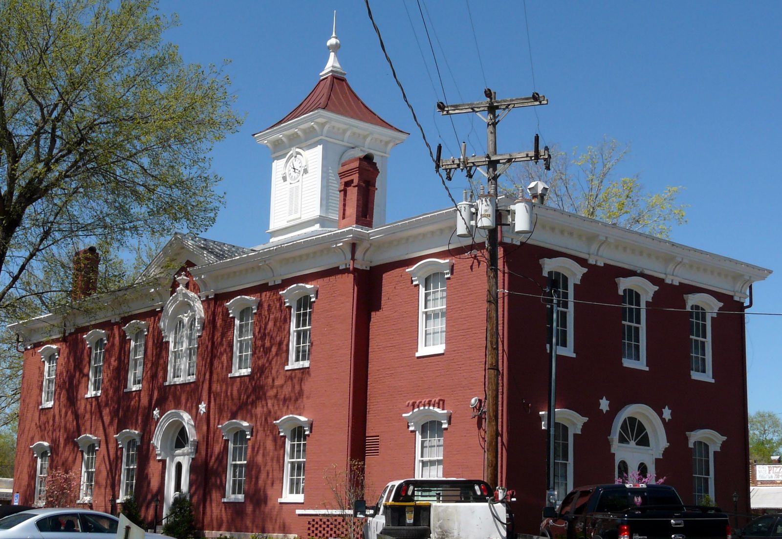 Red brick two-story courthouse with a white cupola and clock