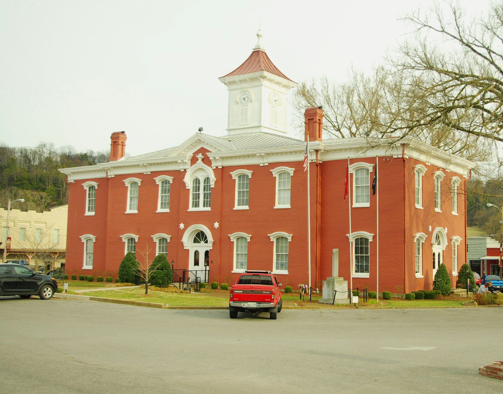 Red brick courthouse with a white cupola, seen across the street