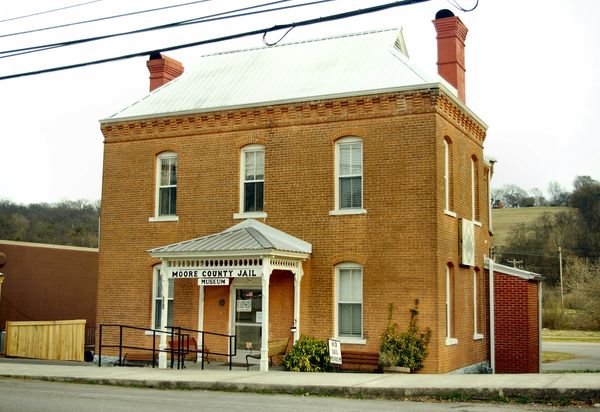 Two-story red brick jail building with a small white porch