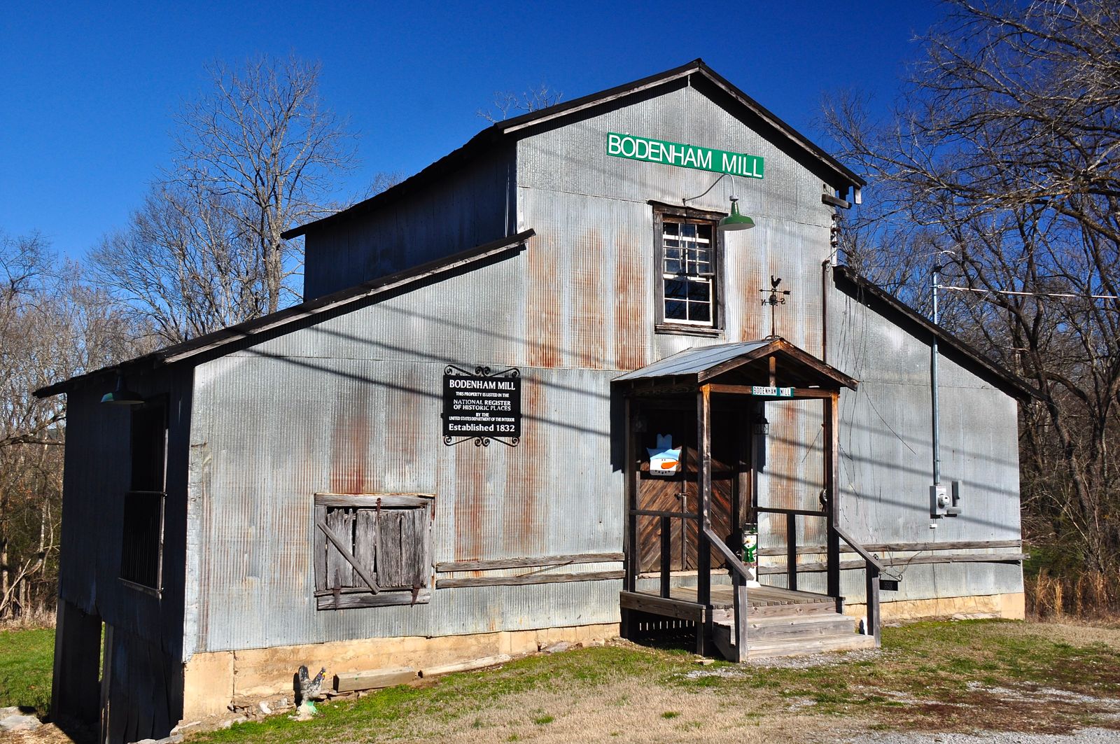 Weathered metal-sided mill building with a small porch