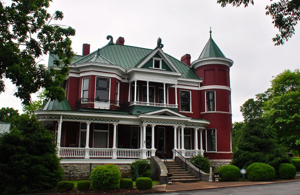 Red brick Victorian house with a corner turret and wraparound porch