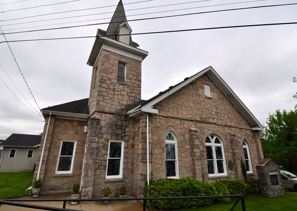 Stone church with a square bell tower and arched windows