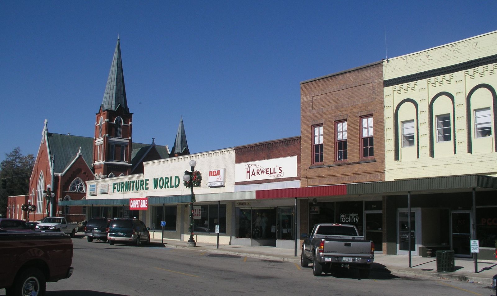 Two-story brick storefronts and a church steeple on the Pulaski square