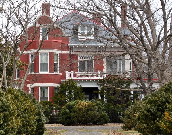 A two-story house with a front porch behind a lawn