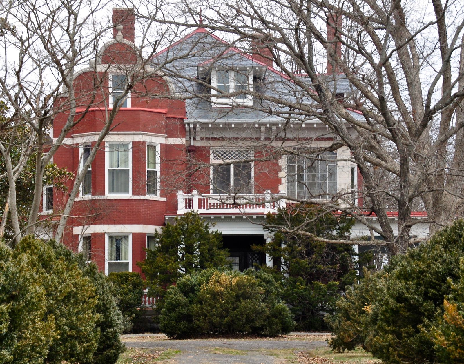A two-story house with a front porch behind a lawn