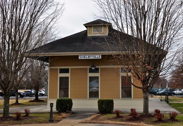 A small yellow frame railroad depot with a dark roof
