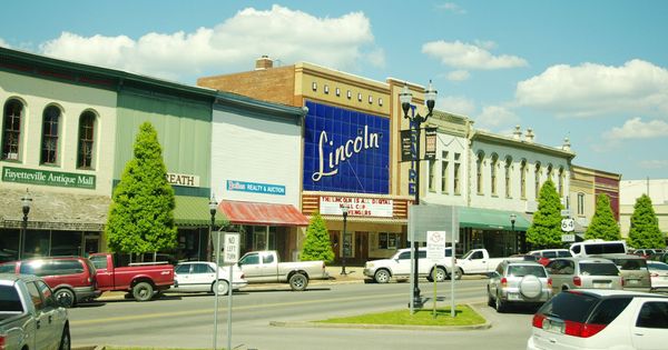 Two-story brick storefronts along College St. E. on the north side of the Fayetteville square, with the blue Lincoln Theatre sign, in 2015