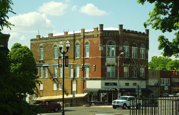 Three-story red brick commercial building with arched windows on a downtown corner