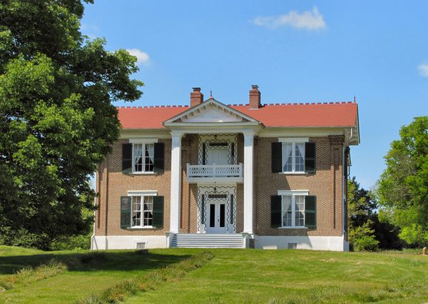 Two-story brick house with a red roof and white columned porch